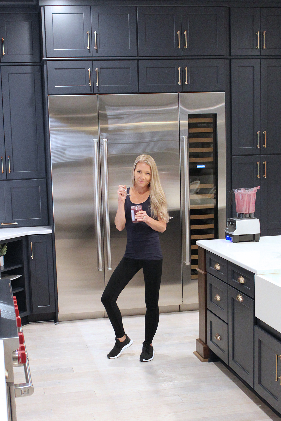 blonde fitness girl holding healthy berry smoothie gourmet kitchen